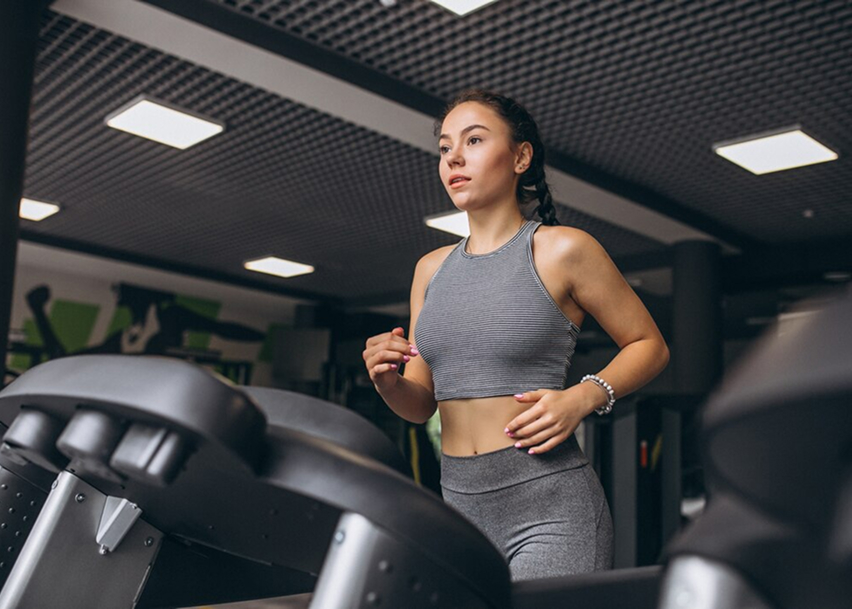 Девушка в тренажерном зале занимается на беговой дорожке 